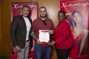 Lidé držící certifikáty před propagačními plakáty.