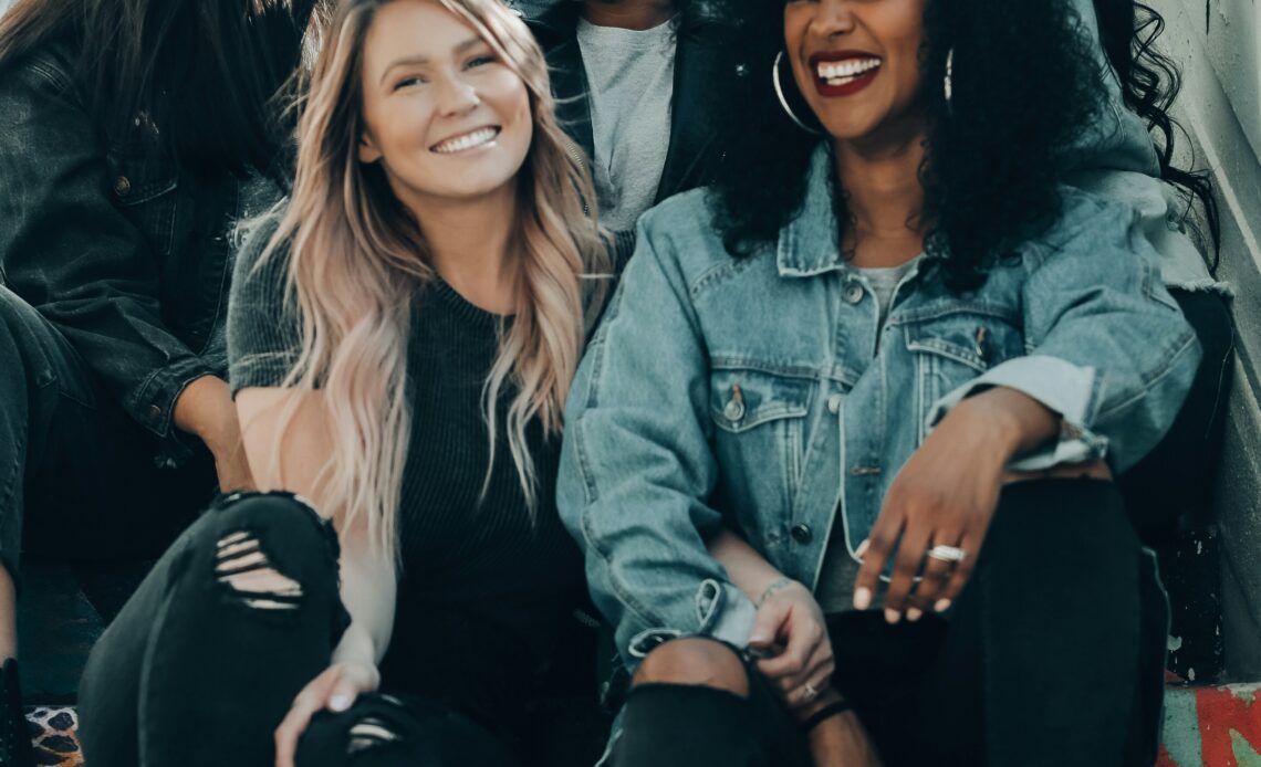 Group of smiling women seated on steps.