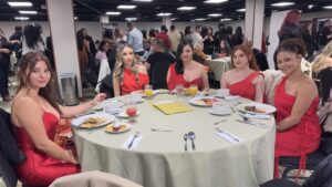 Five women in red dresses at a banquet
